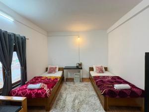 two beds in a room with a window at Divine Homestay Dirang in Dirang Dzong