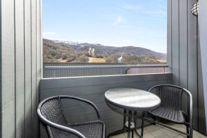 a balcony with two chairs and a table and a window at Squatters Run 26 in Thredbo