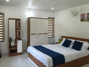 a bedroom with a large bed with blue pillows at Quiet Canopy homestay in Padinjarathara