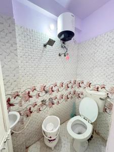 a bathroom with a toilet and a sink with flowers on the wall at Khandelwal Guest House in Ujjain