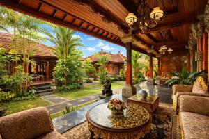 an outdoor living room with a table and chairs at Puri Anyar Ubud by Puri Signatures in Ubud
