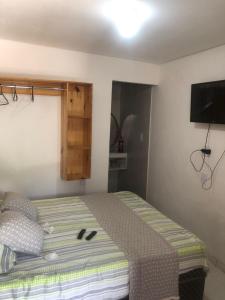 a bedroom with a bed with a flat screen tv at Pousada da Neném - Quarto Tangerina in Campina Grande