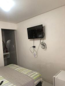 a bedroom with a tv on the corner of a wall at Pousada da Neném - Quarto Tangerina in Campina Grande