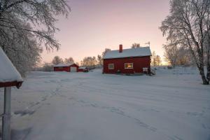 a red barn in a snow covered field at Aurora Lodge in Bjørnevatn