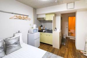 a bedroom with a white bed and a kitchen at コーポラス十日市 - supported by COCOSTAY in Hiroshima