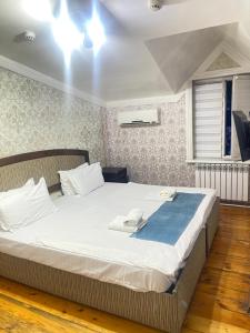 a bedroom with a large bed with two towels on it at GLOBUS Avenue Hotel in Yakkasaray