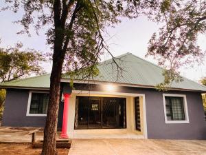 a blue house with a tree in front of it at Unogwaja Rest in Marloth Park
