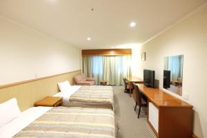 una camera d'albergo con due letti e una scrivania di Station Hotel AU a Tsu