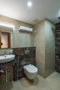 a bathroom with a toilet and a sink at Hotel Vilvah in Coimbatore +17 photos