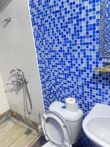 a blue tiled bathroom with a toilet and a sink at GLOBUS Avenue Hotel in Yakkasaray