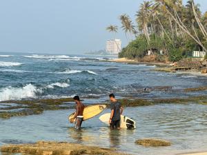 two men standing in the ocean with their surfboards at Surf Lodge Madiha in Matara
