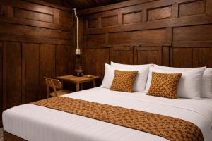 a bedroom with a large bed with a wooden wall at Dapur Alit Villas in Yogyakarta