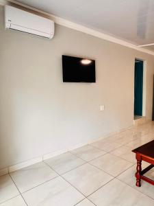 a living room with a tv on a white wall at Unogwaja Rest in Marloth Park