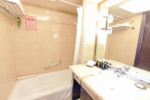a bathroom with a sink and a tub and a mirror at Ramada Plaza Tianlu Hotel in Wuhan