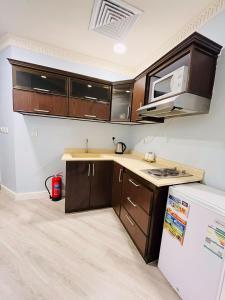 a kitchen with wooden cabinets and a white refrigerator at صفاء المسكن in Dammam +18 photos