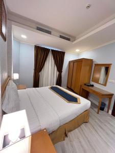 a hotel room with a large bed and a desk at صفاء المسكن in Dammam