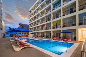 a pool at a hotel with chairs and umbrellas at Decameron Isla Coral Guayabitos, Ramada All-Inclusive Resort in Rincon de Guayabitos