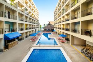 an aerial view of an apartment building with two pools and umbrellas at Decameron Isla Coral Guayabitos, Ramada All-Inclusive Resort in Rincon de Guayabitos +70 photos