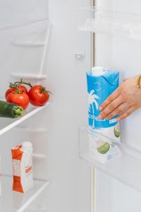 a person holding a carton of milk in an open refrigerator at Quest Goulburn North in Goulburn