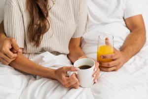a couple sitting in bed with a cup of coffee and a glass of orange juice at Quest Goulburn North in Goulburn +2 photos