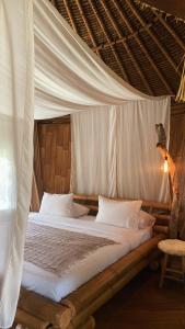 a bed in a room with a mosquito net at Alpaca Lodge in Tanah Lot