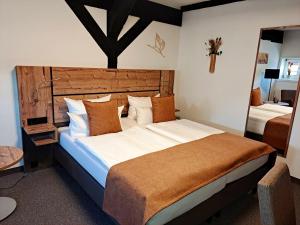a bedroom with a large bed with a wooden headboard at Hotel Am Markt & Brauhaus Stadtkrug in Ueckermünde +143 photos