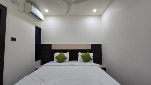 a bedroom with a large bed with green pillows at SHRI DIVYAM Hotel & Restaurant in Bhopal