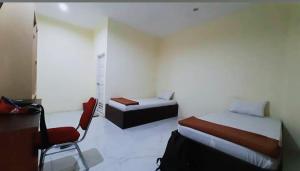 a room with two beds and a chair in it at Hotel Permata Inn Ball Room Seroja in Kualakapuas