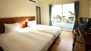 a bedroom with a bed and a tv and a window at Feliz Villa Suite Miyakojima Ueno in Miyako-jima