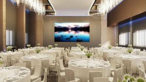a banquet hall with white tables and chairs and a screen at Brisdale International Kuala Lumpur in Kuala Lumpur
