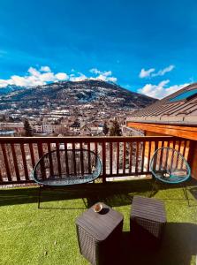 a balcony with two chairs and a view of a city at Comme à la maison à la montagne in Briançon