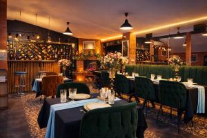 a restaurant with tables and green chairs and wine bottles at Kinor David Glatt Kosher Hotel in Tbilisi City