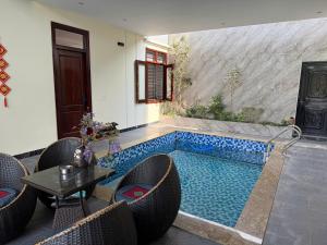 a swimming pool with chairs and a table in a room at De' Mon Villa in Làng Tong Tchoung +20 photos