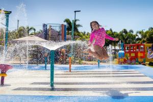 a little girl jumping in the water at a water park at Ingenia Holidays Conway Beach in Conway