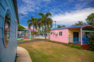 a pink and yellow building with palm trees in a park at Ingenia Holidays Conway Beach in Conway