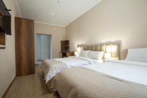 a bedroom with two beds and a flat screen tv at Kinor David Glatt Kosher Hotel in Tbilisi City +43 photos