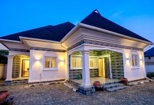 a white house with a pitched roof at Gustavó Premium Apartment in Benin City