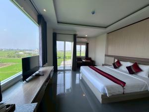 a bedroom with a bed and a television and a balcony at Chiang Rai Airport Hotel in Ban Fang Min