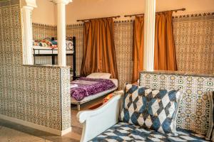 a bedroom with a bed and a mirror and a couch at Hostel Assafar in Ouarzazate