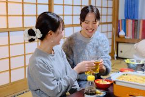 two women sitting at a table drinking beer at 古民家宿Tabi湊 in Hitachinaka