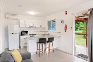 a kitchen with white cabinets and a counter with stools at Ingenia Holidays Conway Beach in Conway