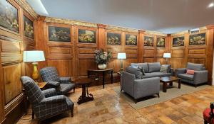 a waiting room with chairs and tables and paintings at Hotel de La Font Peralada in Peralada