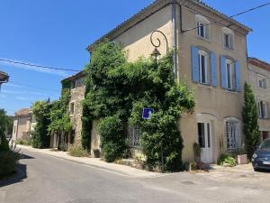 a building with a tree on the side of a street at Le jardin de Grignan in Réauville