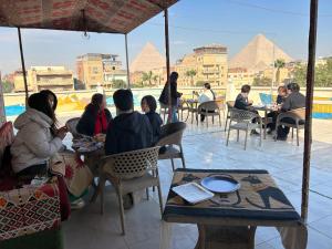 a group of people sitting at tables with pyramids in the background at Matto Pyramids Inn in Cairo