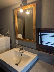 a bathroom with a white sink and a mirror at 川まで徒歩1分川沿いにある一軒宿あせみ in Nakajima