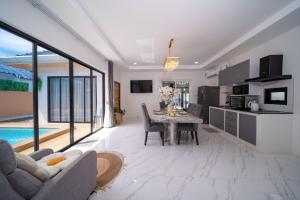 a living room with a table and a kitchen with a pool at Mango Breeze Villa in Ban Nong Chaeng