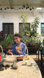 a young girl sitting at a table with plants at Arasu Homestay in Antarasante