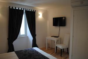 a bedroom with a bed and a chair and a window at Rooms Piazzetta in Cres