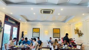 a group of people sitting at tables in a restaurant at Salina Hotel Ninh Binh in Ninh Binh