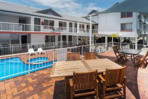 a patio with a wooden table and chairs next to a pool at Sunshine Beach Resort in Gold Coast